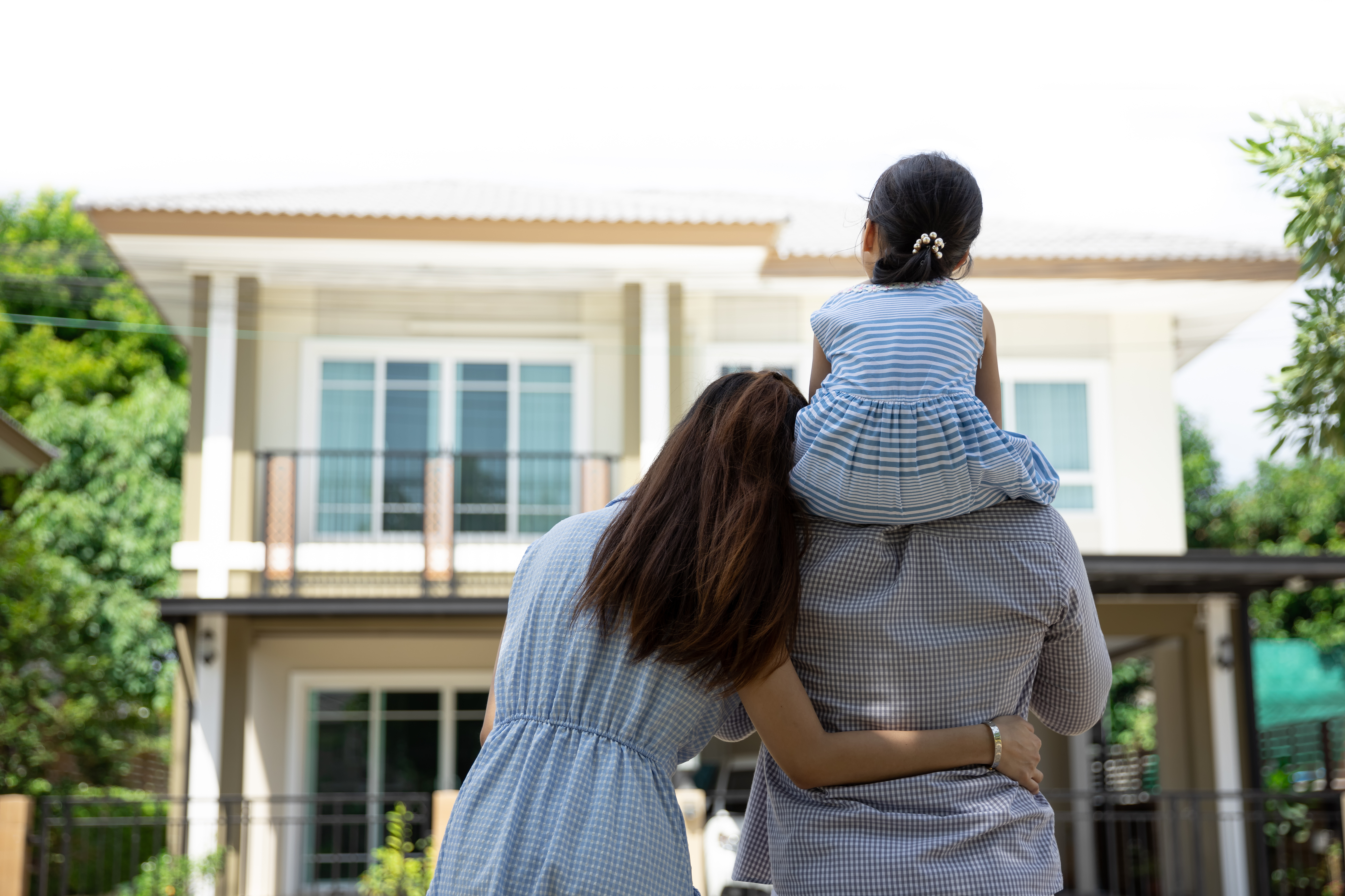family of three, standing outside of their new home